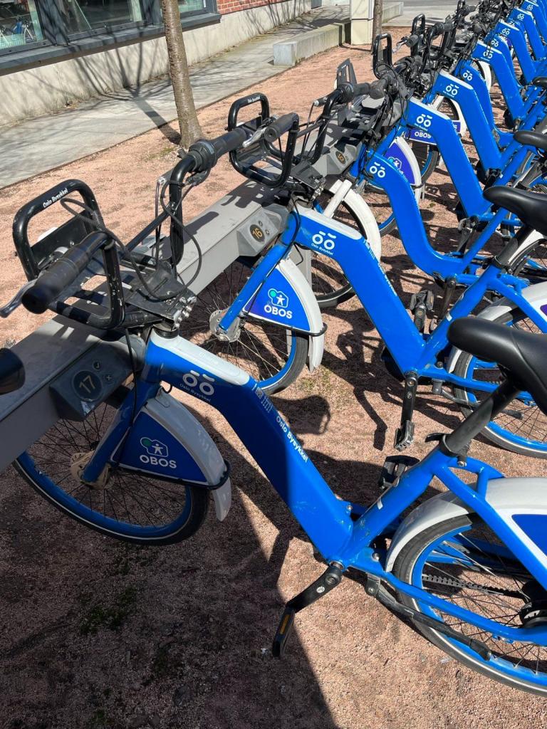 Row of Oslo city bikes, all blue with racks on the front.